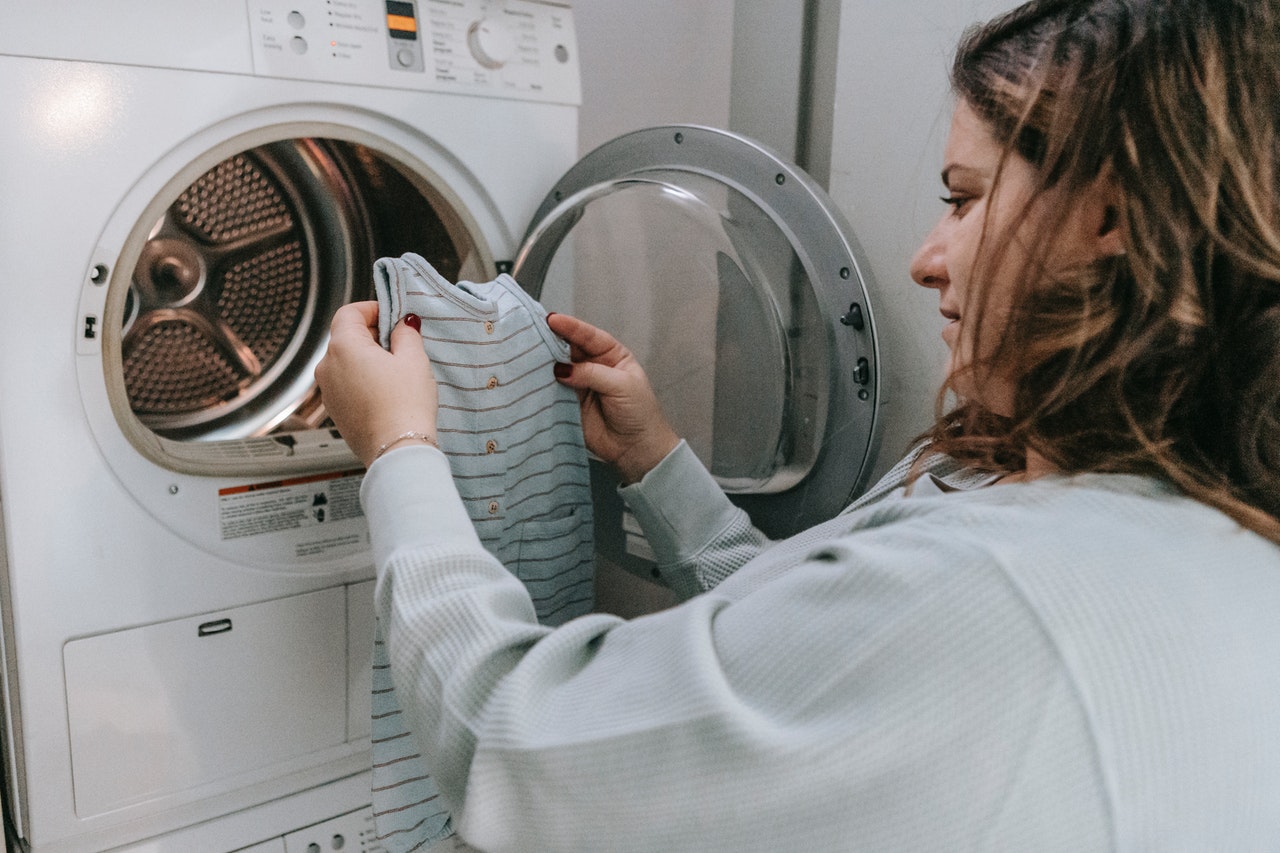 Kobieta wkłada brania do małej pralki typu Slime